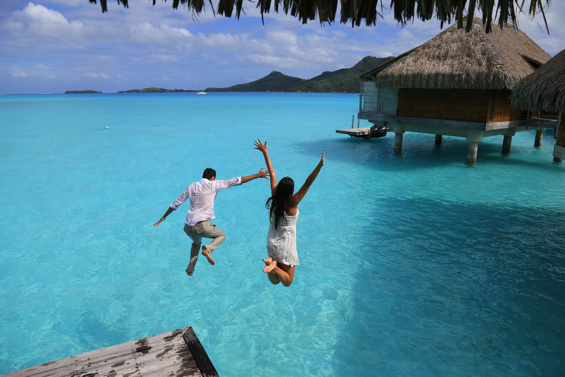 Couple jumping from overwater bungalow